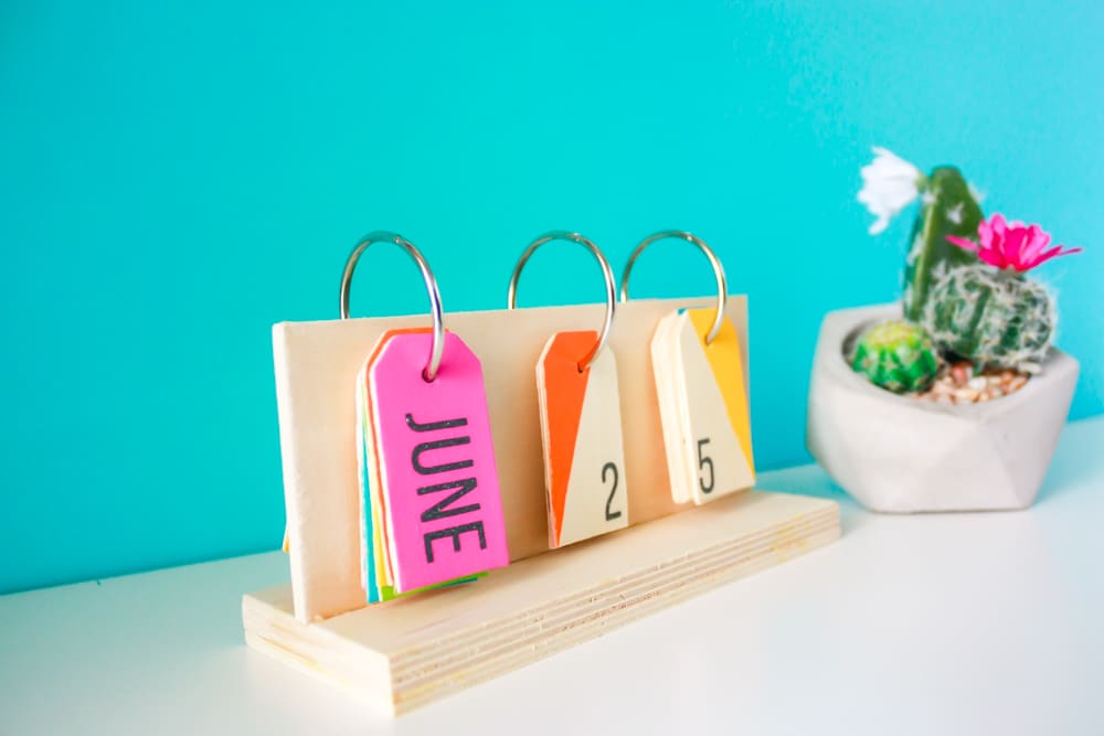 How to make a perpetual calendar for a colorful way to display the date! You'll need wood pieces, wooden tags, glue, metal rings, paint, and a drill.