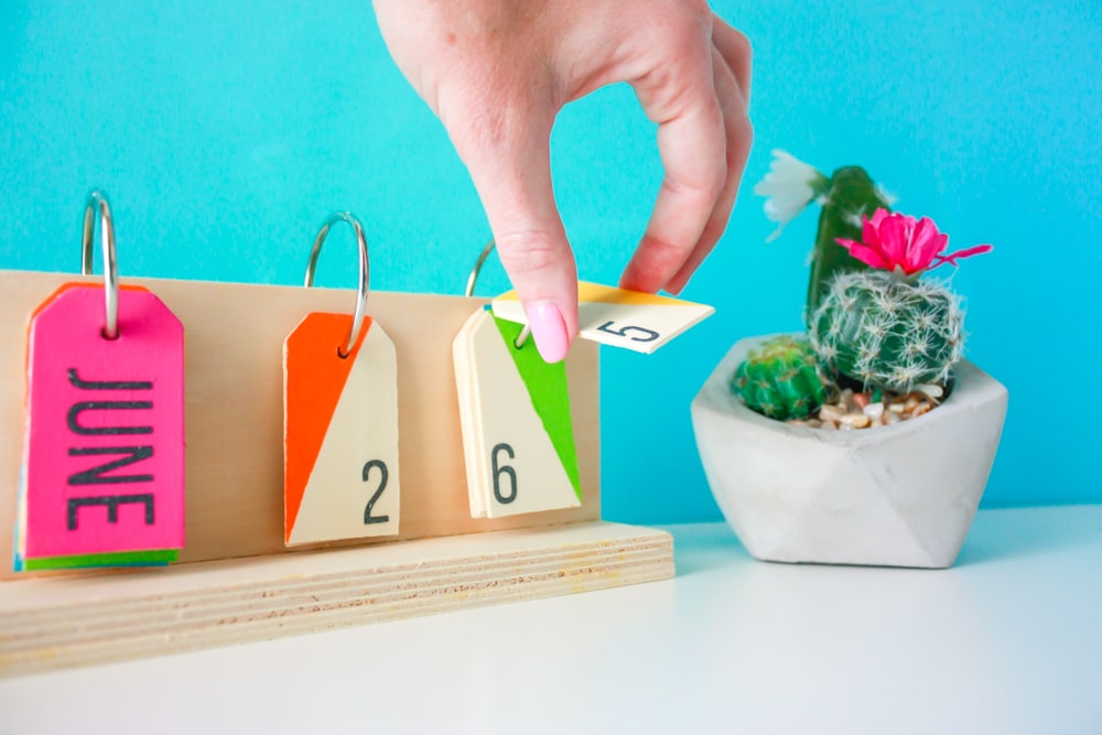 How to make a perpetual calendar for a colorful way to display the date! You'll need wood pieces, wooden tags, glue, metal rings, paint, and a drill.