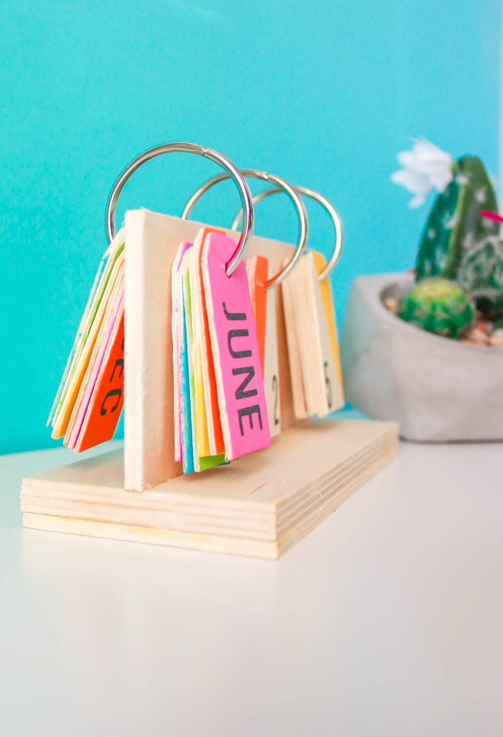 How to make a perpetual calendar for a colorful way to display the date! You'll need wood pieces, wooden tags, glue, metal rings, paint, and a drill.