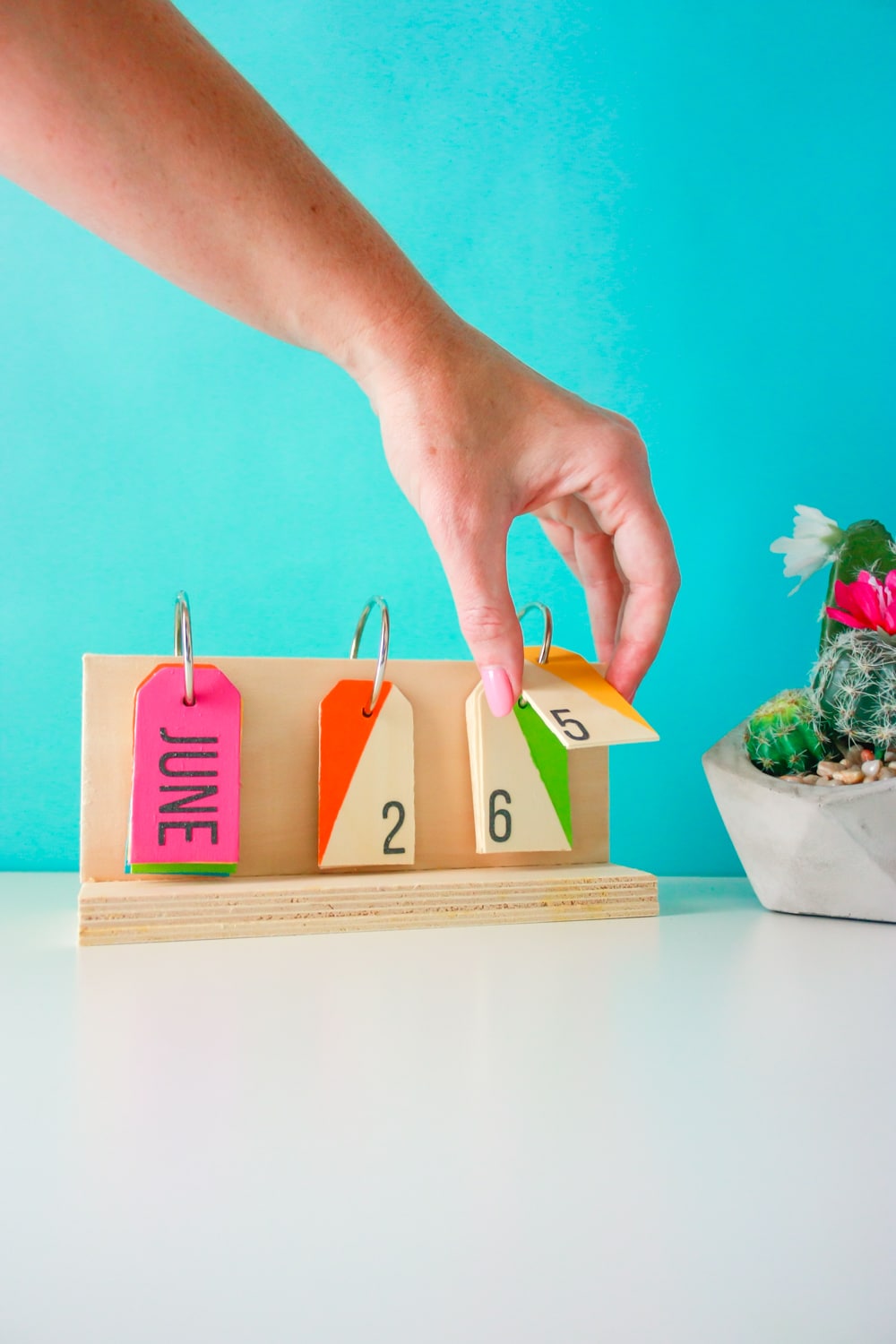 How to make a perpetual calendar for a colorful way to display the date! You'll need wood pieces, wooden tags, glue, metal rings, paint, and a drill.