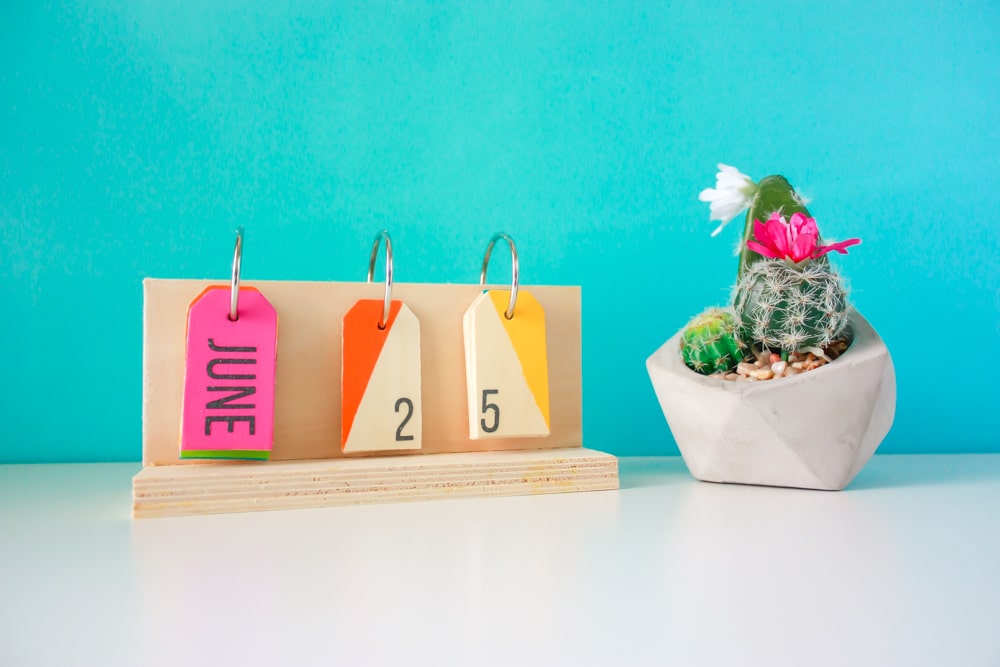 How to make a perpetual calendar for a colorful way to display the date! You'll need wood pieces, wooden tags, glue, metal rings, paint, and a drill.