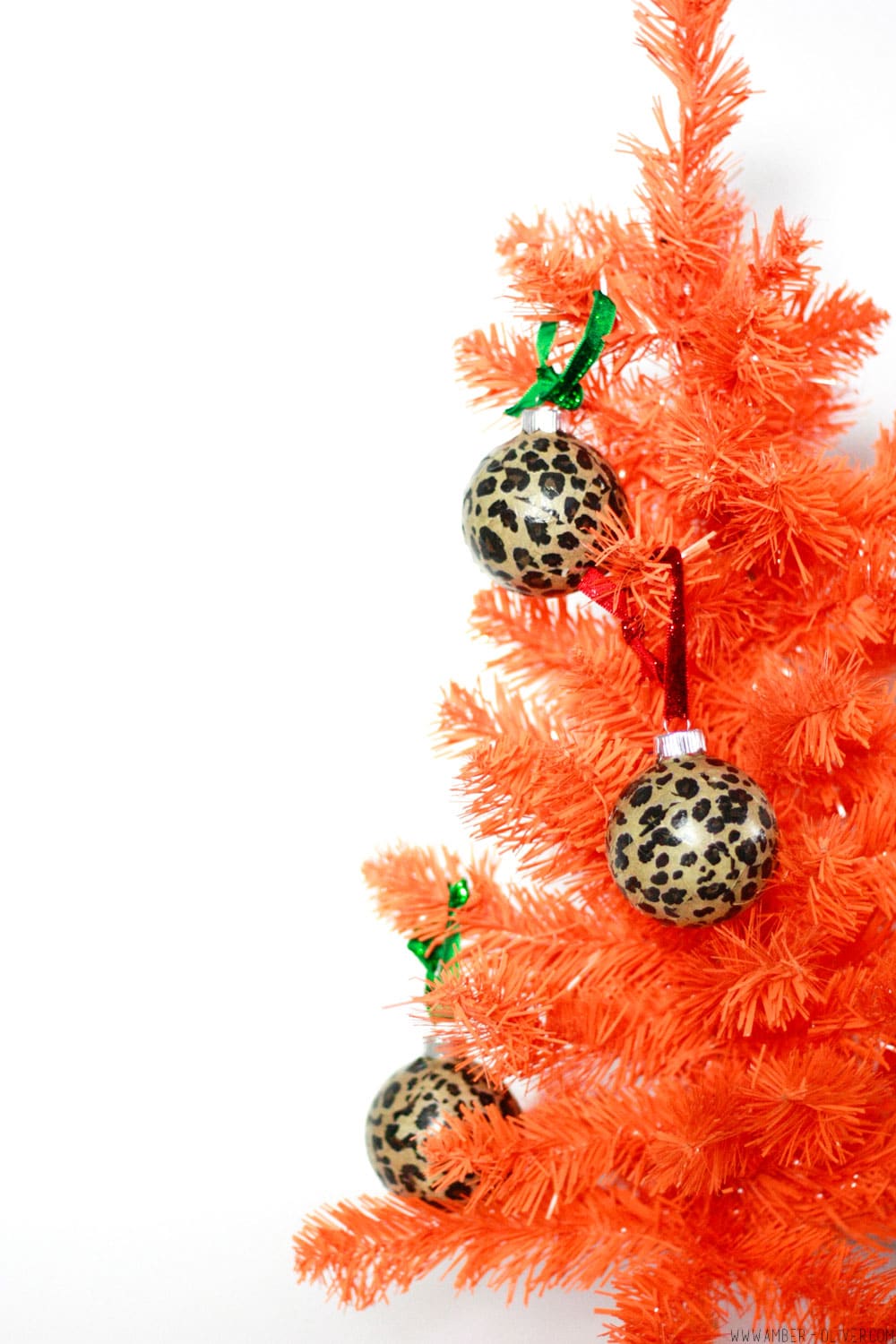 DIY Leopard Print Ornaments hung on an orange tree. these are Easy to make modge podge tissue paper Christmas ornaments!