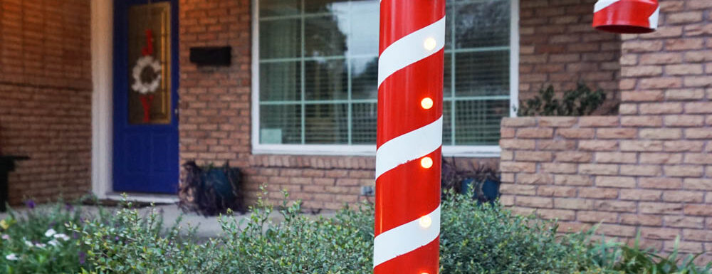 DIY Lighted PVC Candy Cane standing tall outside house