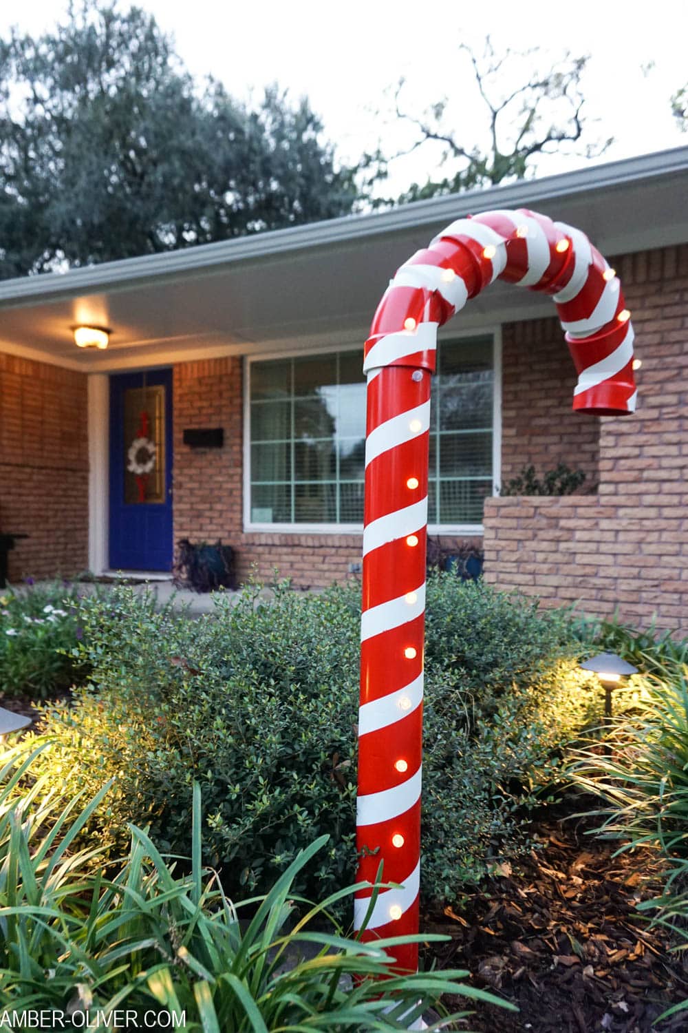 DIY Lighted PVC Candy Cane standing tall outside house