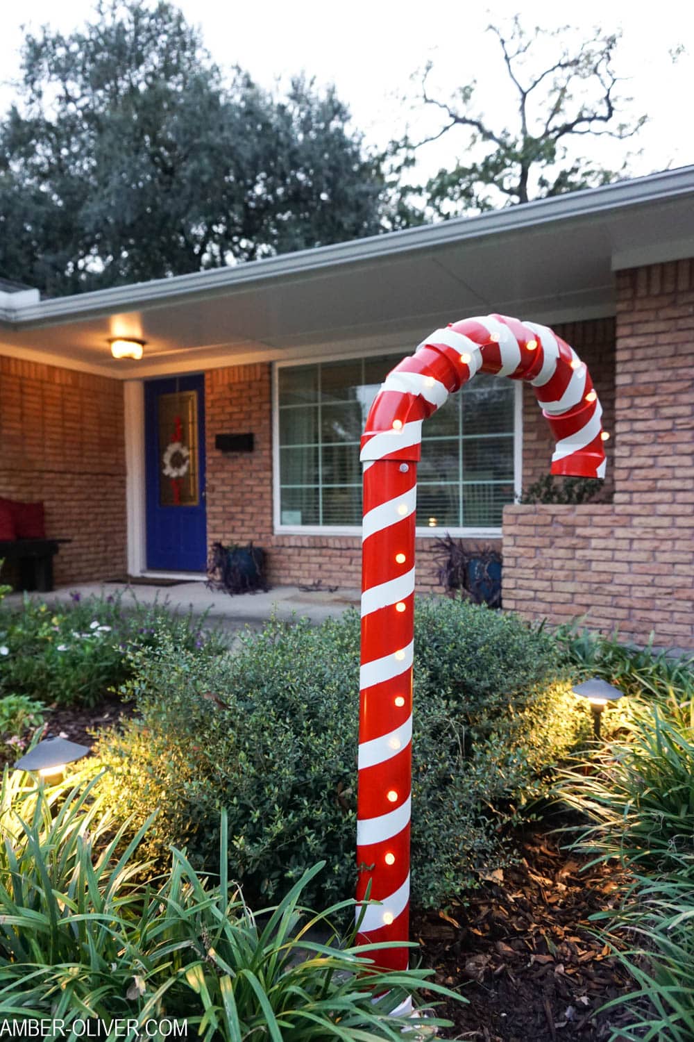 DIY Lighted PVC Candy Canes in garden in front of house