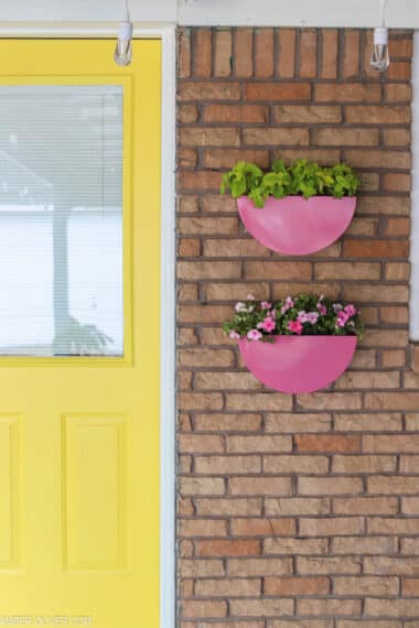 pink painted metal planters by a yellow door