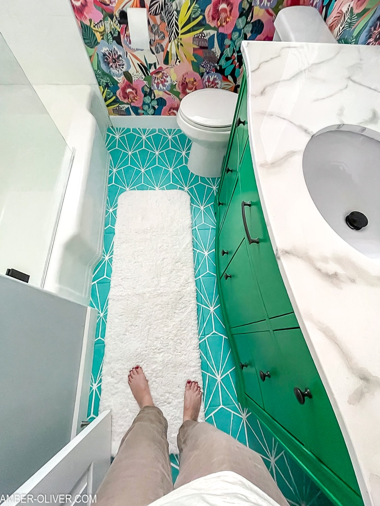 birdseye view of bold bathroom makeover with white rug over painted tile floor