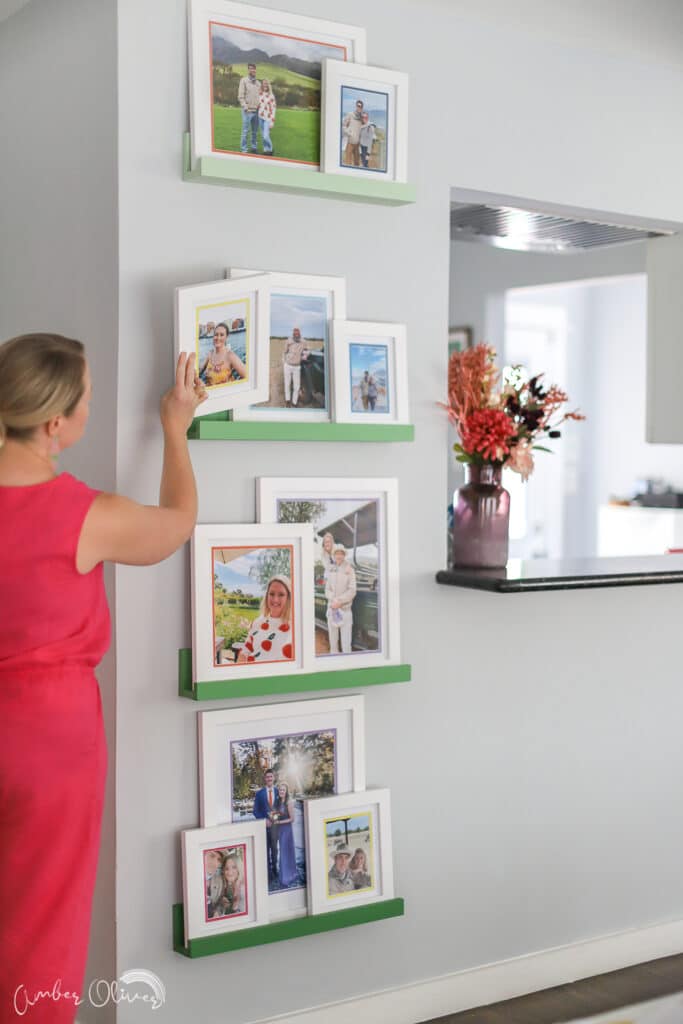 amber oliver putting art to frames on colorful picture ledge gallery wall