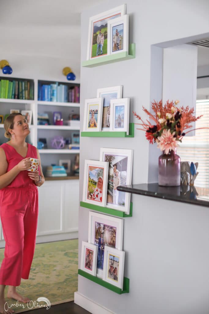 amber oliver looking at colorful picture ledge gallery wall