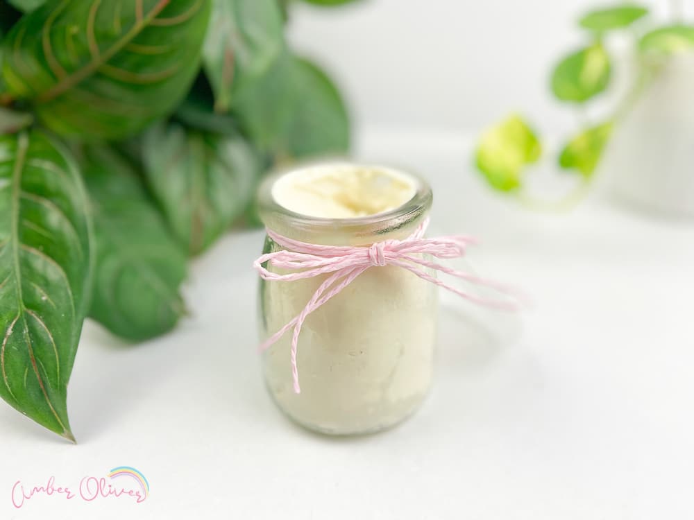 diy whipped lotion stored in a glass jar with a pink ribbon