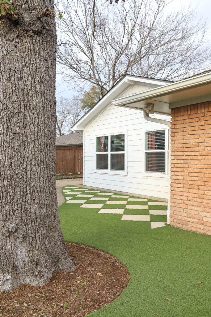 view of house, paver stones and artificial turf